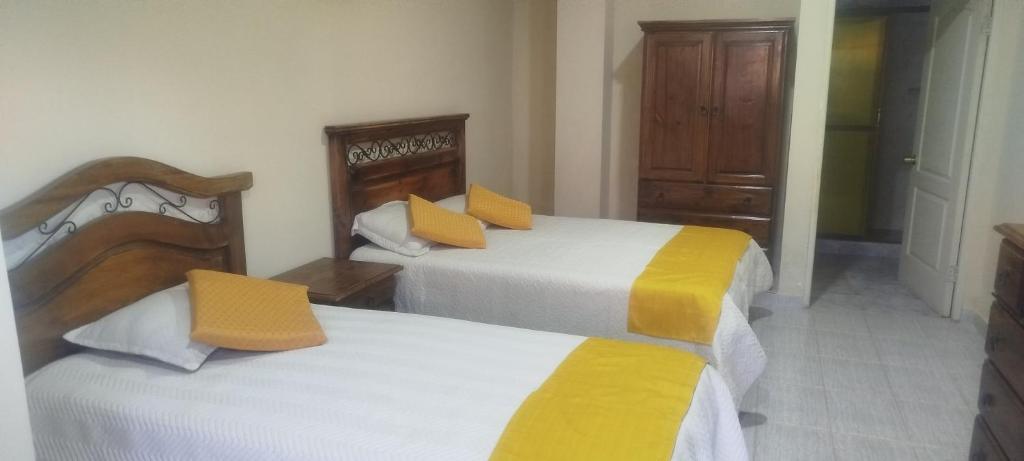 a bedroom with two beds with yellow and white sheets at Hostal Cadena in Tupiza