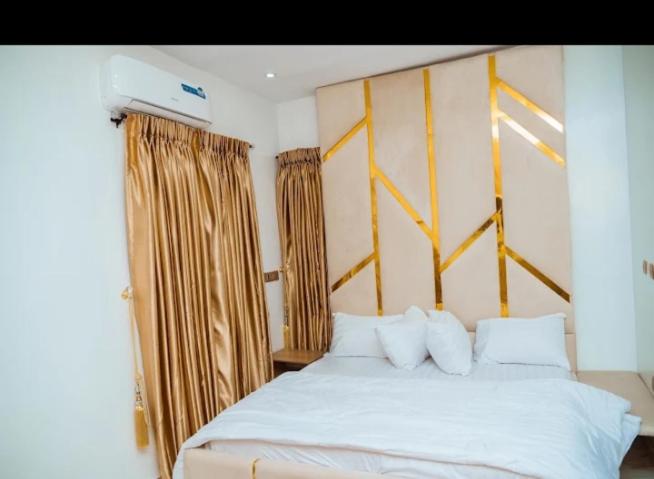 a bedroom with a white bed with white pillows at Blu Atlantic Apartment in Oshogbo