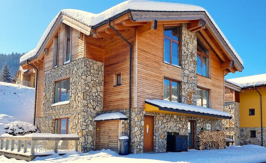 a large wooden house with snow on the ground at Apartment ALFA with jacuzzi in Belá