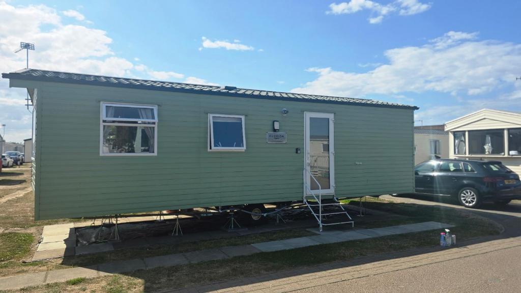 a green tiny house in a parking lot at california cliffs caravan 2 dunlin in Scratby