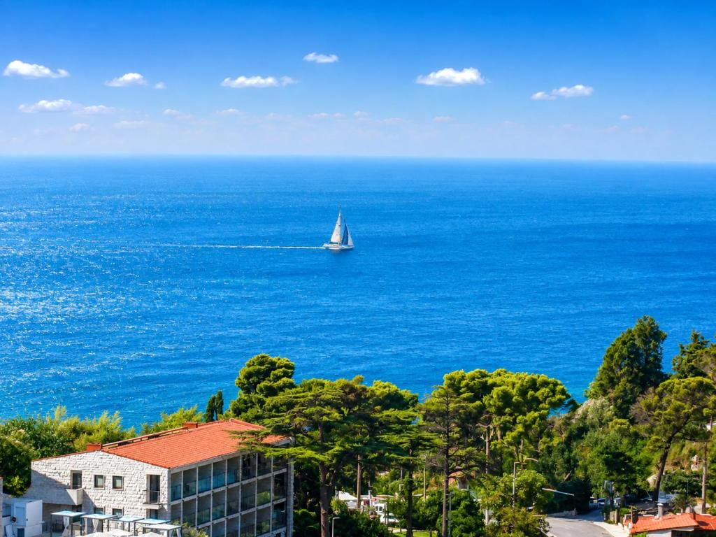 a sail boat in the ocean with a building at Tina Rooms in Ulcinj