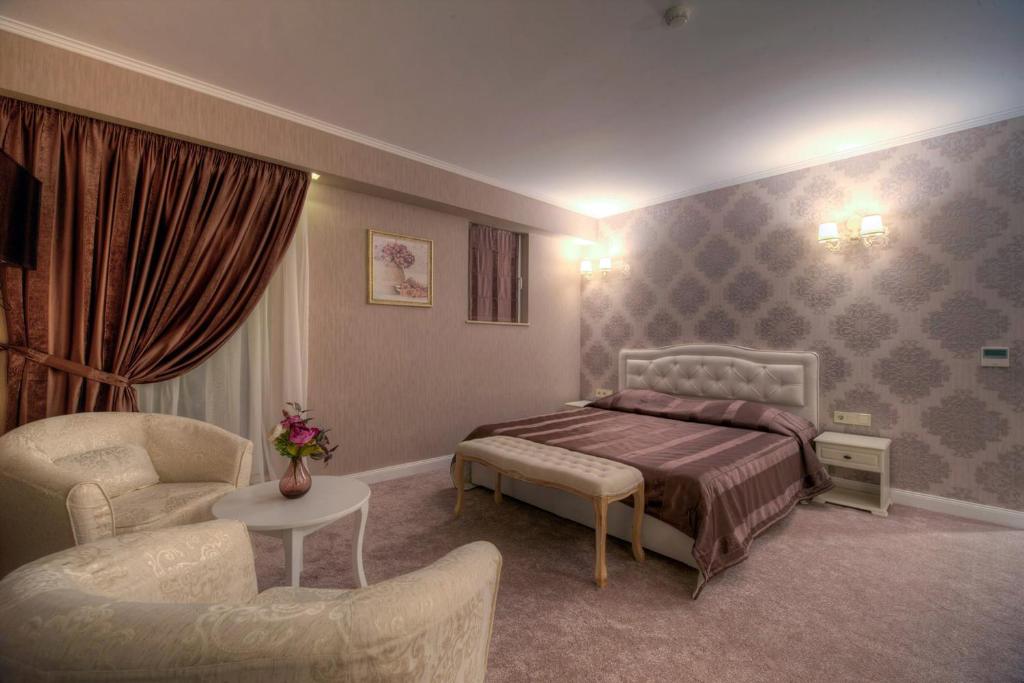 um quarto com uma cama, um sofá e uma cadeira em Family Hotel Agoncev em Sófia