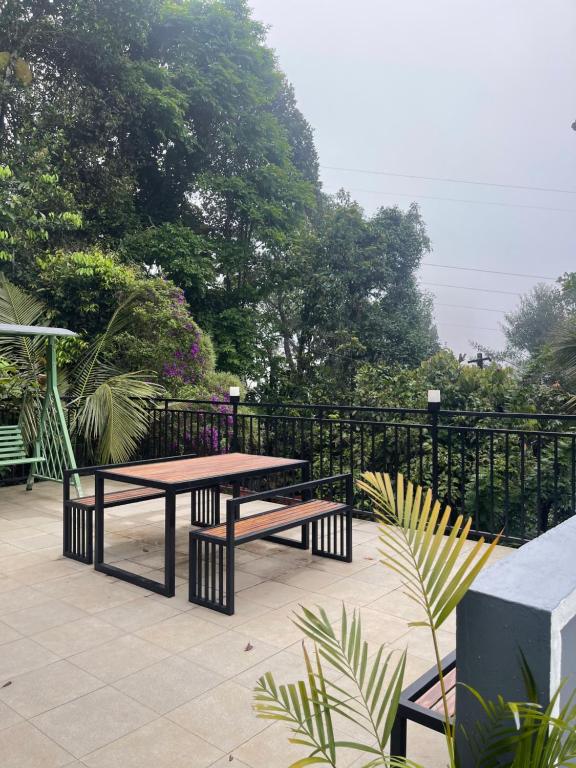 a picnic table and benches in front of a fence at Neev holiday homes in Vythiri