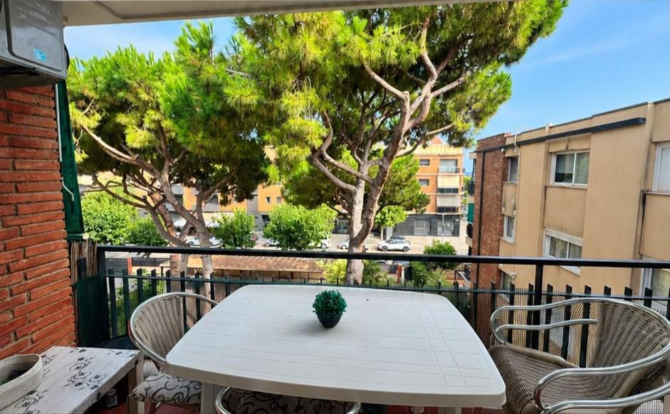 a white table and chairs on a balcony with trees at Apartamento Cabrera Montserrat in Cabrera de Mar