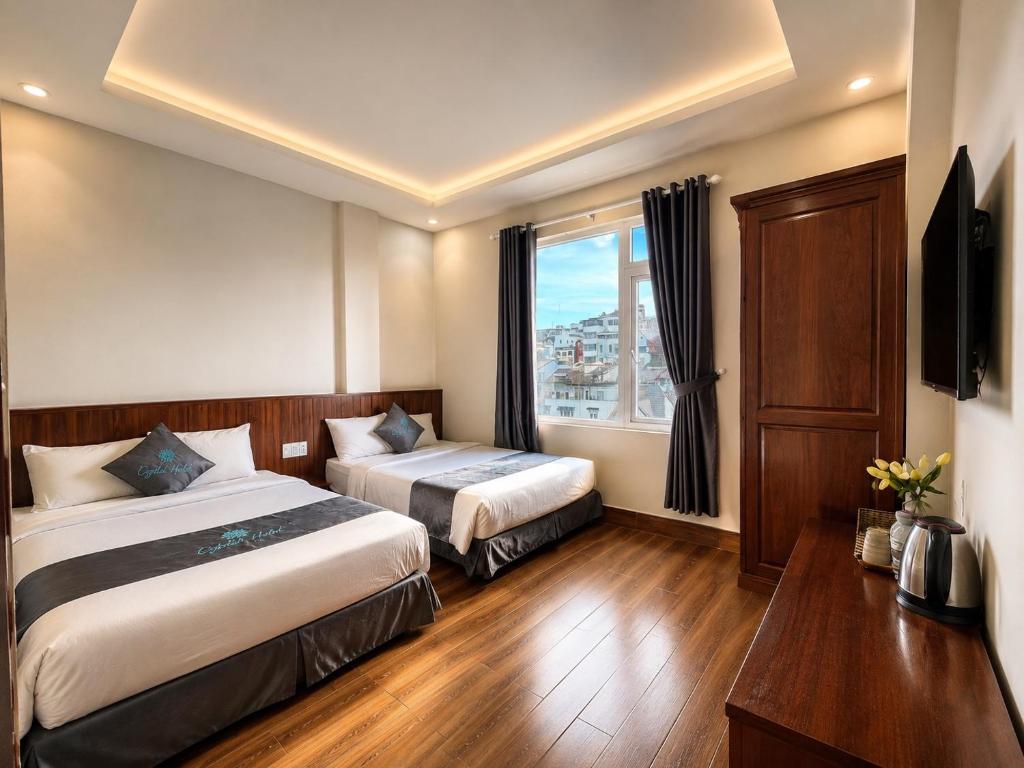 a hotel room with two beds and a window at CaRa Hotel Đà Lạt in Da Lat
