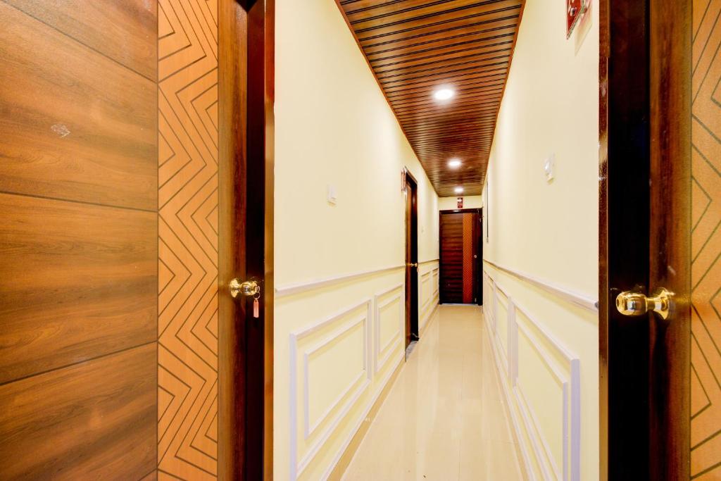 a hallway with white walls and wooden doors at Hotel O Hotel R Pacific in Hyderabad
