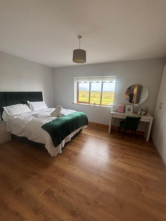 a bedroom with a bed and a desk and a window at Ballyconneely house in Ballyconneely