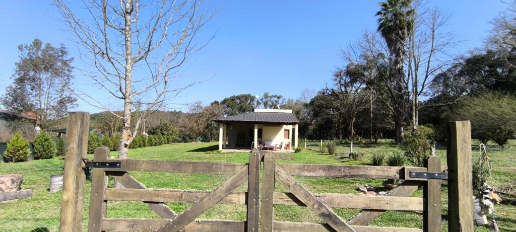 a wooden fence with a gate in front of a small house at Cálida Casa con amplio espacio verde en Raco in Raco