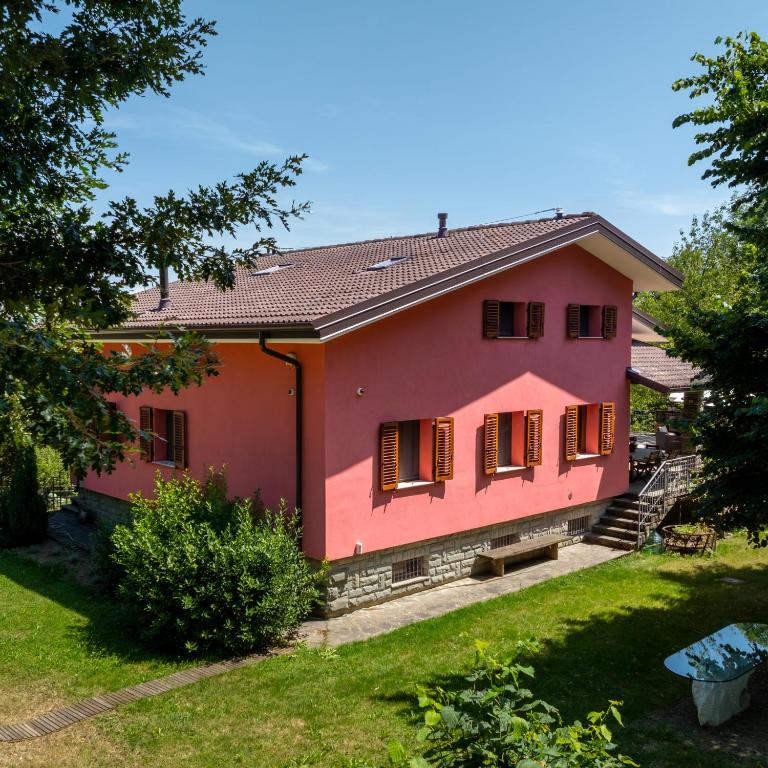 a pink house with red shutters and a yard at I Monelli in Sestola