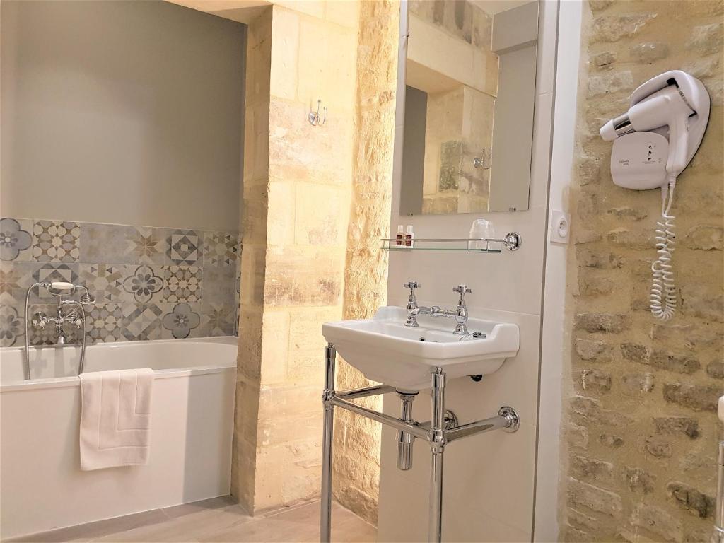 a bathroom with a sink and a bath tub at Le Tardif, Noble Guesthouse in Bayeux