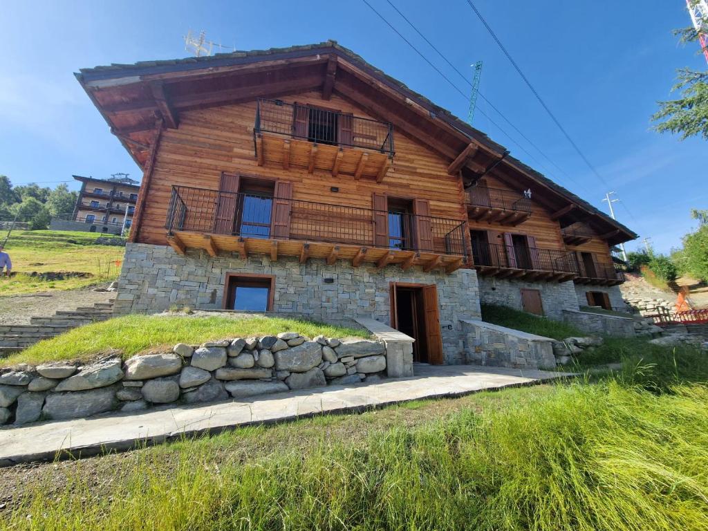 a large wooden house with a stone wall at Chalet du Sky PILA in Cerise