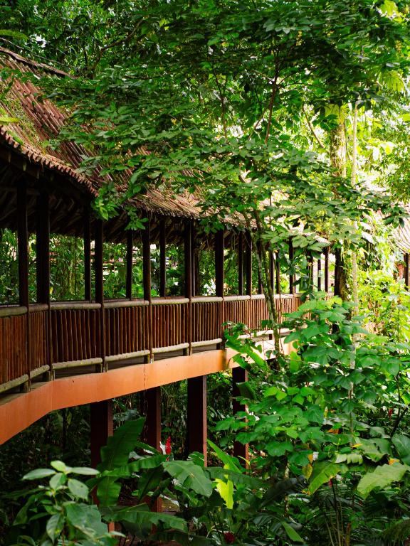 a wooden bridge in a garden with trees at Hotel El Bambu in Sarapiquí