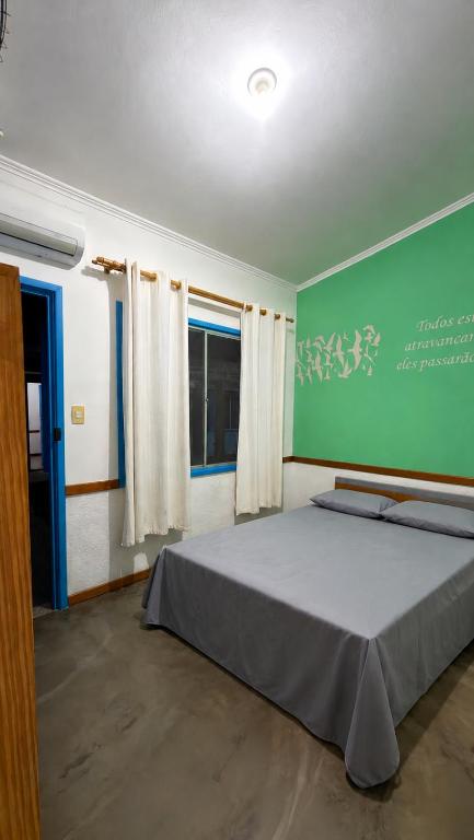 a bedroom with a bed and a green wall at Villa Sempre Viva in São João Batista do Glória