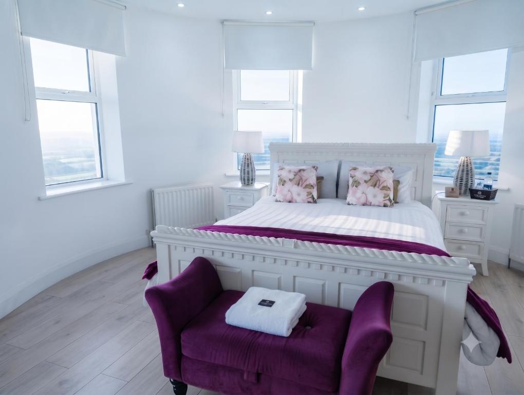 a white bedroom with a white bed and a purple chair at Rathescar Grove Guest House in Drogheda