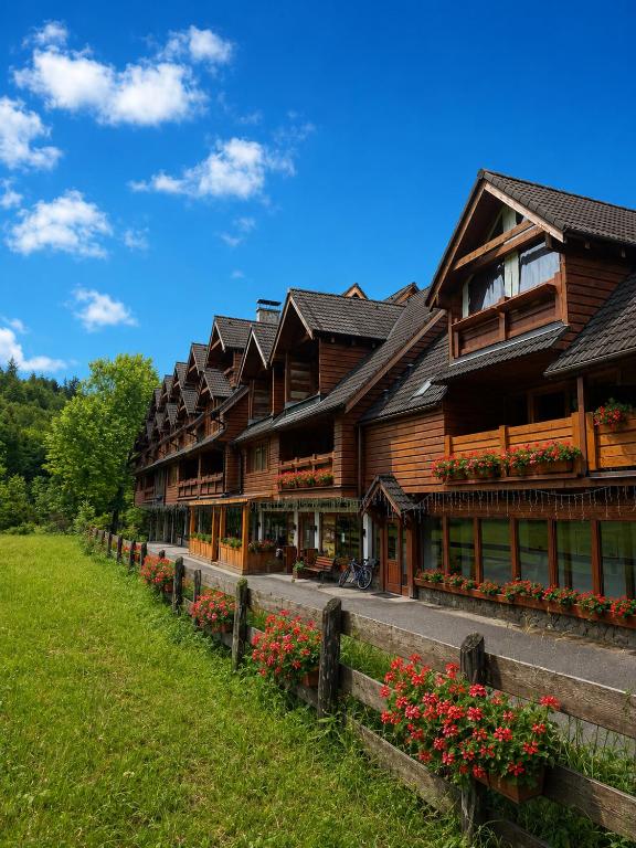 a large wooden building with flowers in front of it at Penzión SIMI in Tatranská Lomnica