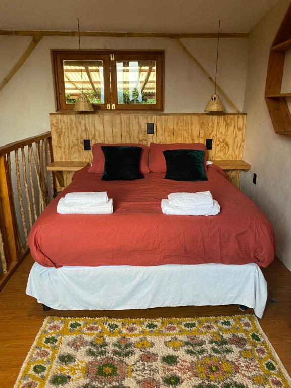 a bedroom with a large red bed with two pillows at Casa Zapote in Sololá