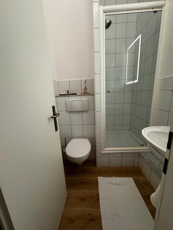 a white bathroom with a toilet and a sink at Jade Villa an der Nordsee in Jaderaltendeich