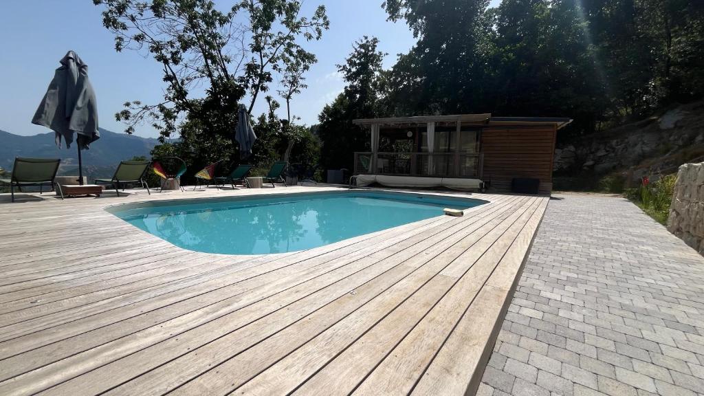 a swimming pool with a wooden deck and a house at Chalet U Castagnu du Jardin de Luiggi in Venaco