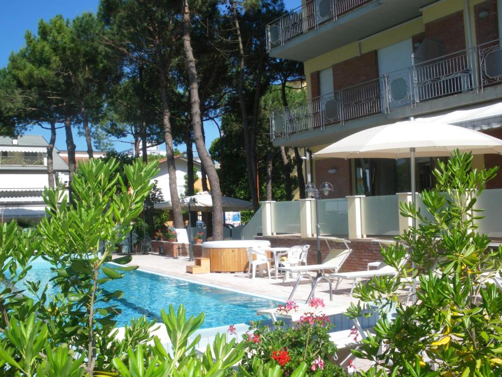 a swimming pool with chairs and an umbrella next to a building at Hotel Ascot in Cervia