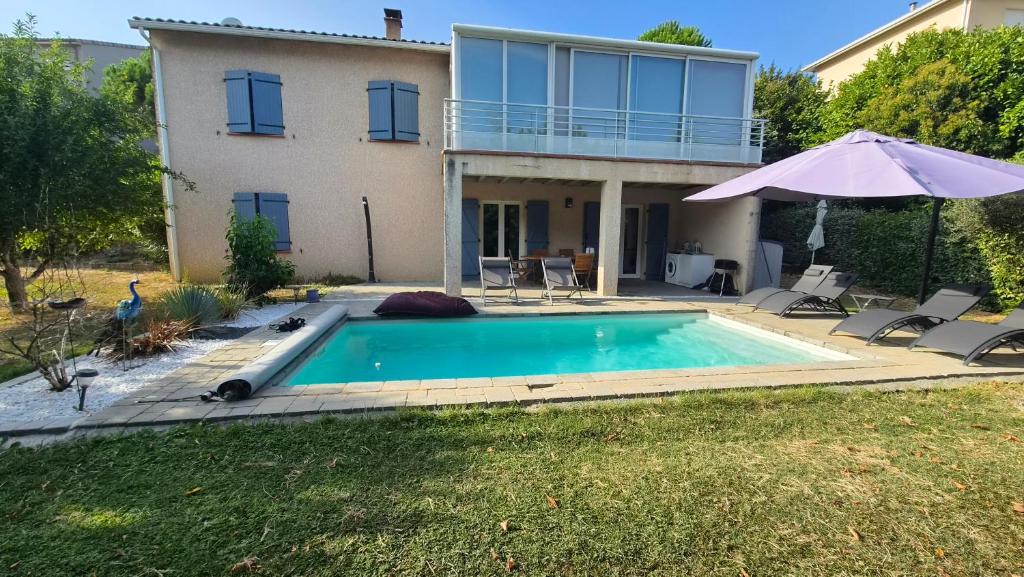 a house with a swimming pool and an umbrella at "L'appart Idéal" in Deyme