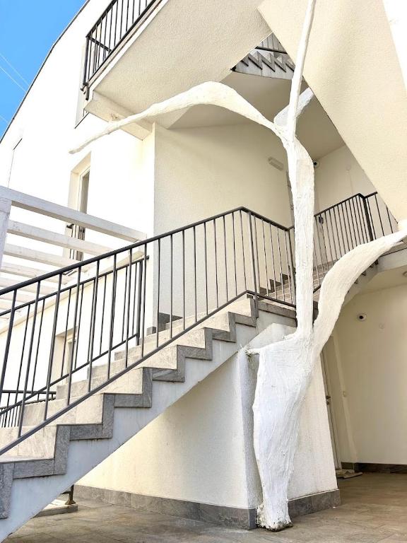 a staircase in a white building with a tree at MostOliva luxury Rooms in Pržno