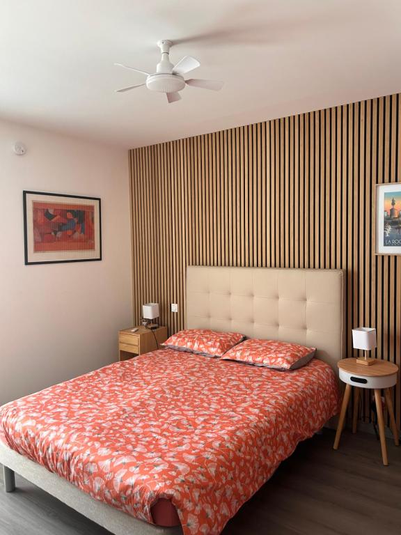 a bedroom with a bed with a red comforter at Chez Olivier et Damien in La Roche-sur-Yon