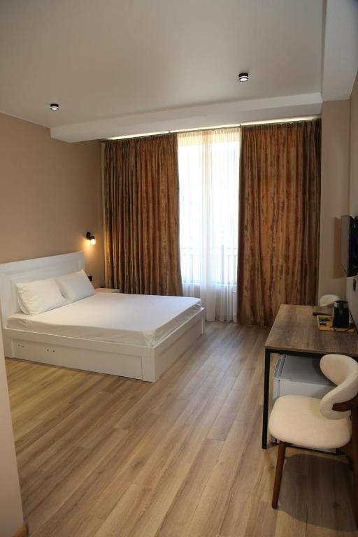 a bedroom with a bed and a desk and a window at Mn Hotel Borjomi in Borjomi