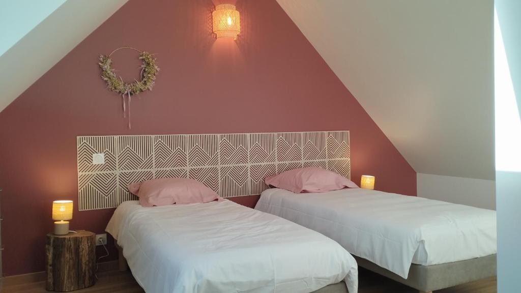 two beds with pink pillows in a attic bedroom at Gîte La Ferme Ecole in Perrou