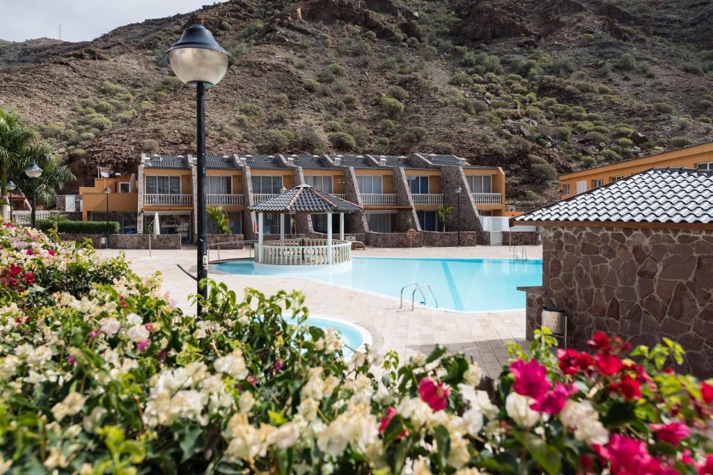 um hotel com uma piscina com uma montanha ao fundo em Ilusión em La Playa de Tauro