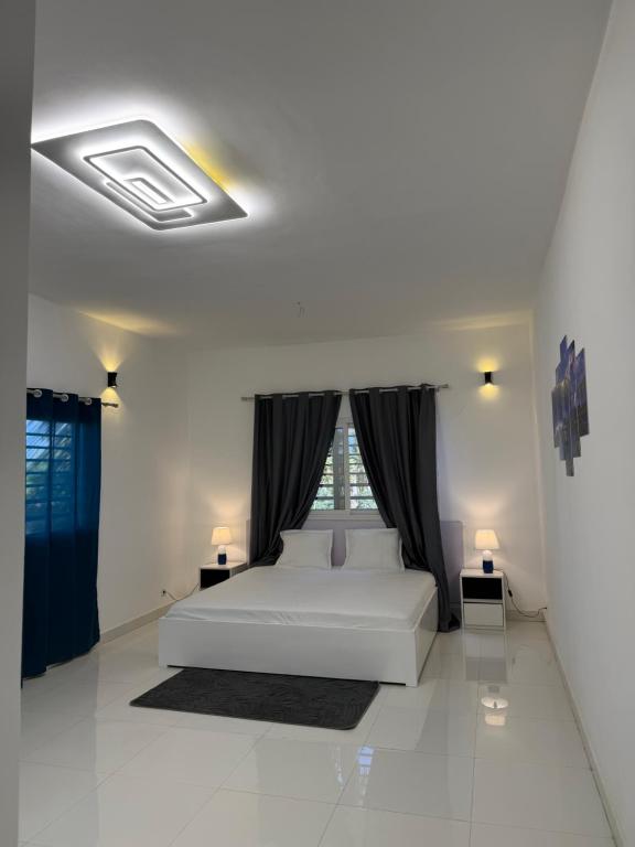 a white bedroom with a bed and a window at C-Appart Residence in Tuléar