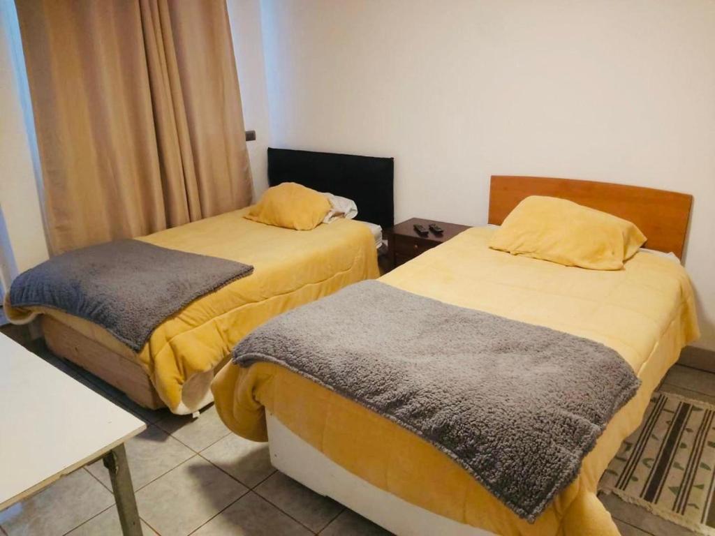a room with two beds with yellow and gray sheets at Hostal D&N servicios 
