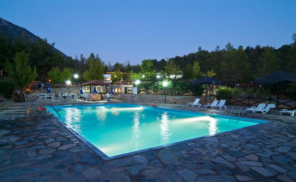a swimming pool at night with chairs and umbrellas at Bungalow - Camping Apollon in Delphi