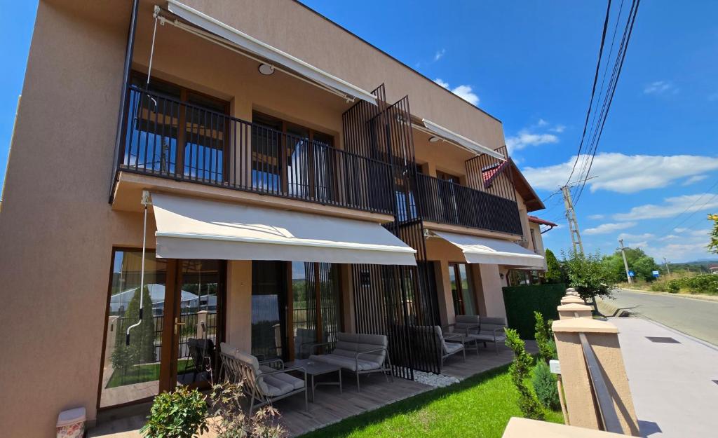 a building with a balcony with chairs and an umbrella at Apartamente Nefeli in Curtea de Argeş