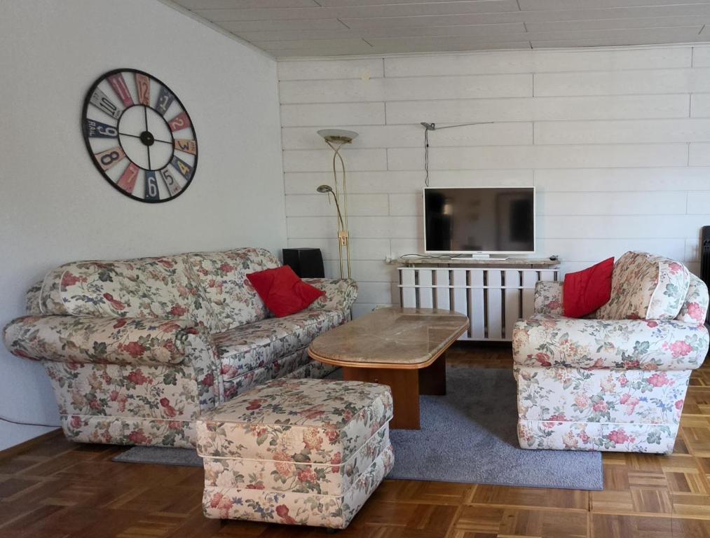 a living room with two chairs and a table and a clock at Ferienwohnung Helena in Markkleeberg