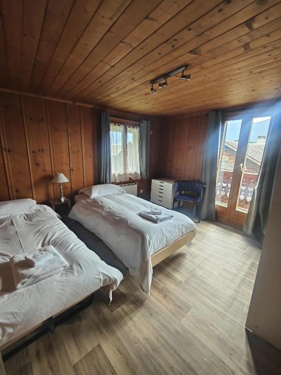a bedroom with two beds and a wooden ceiling at Hotel les Touristes in Verbier