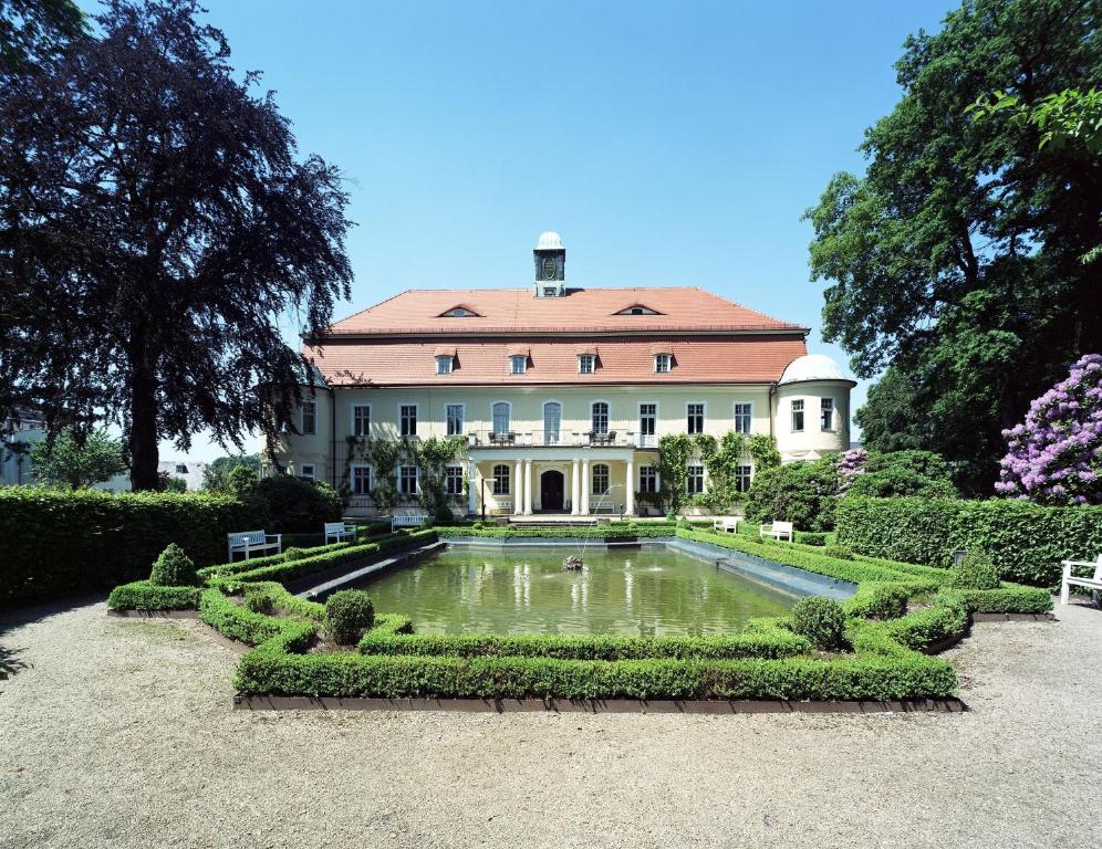 ein großes Haus mit einem Teich davor in der Unterkunft Hotel Schloss Schweinsburg in Neukirchen-Pleiße