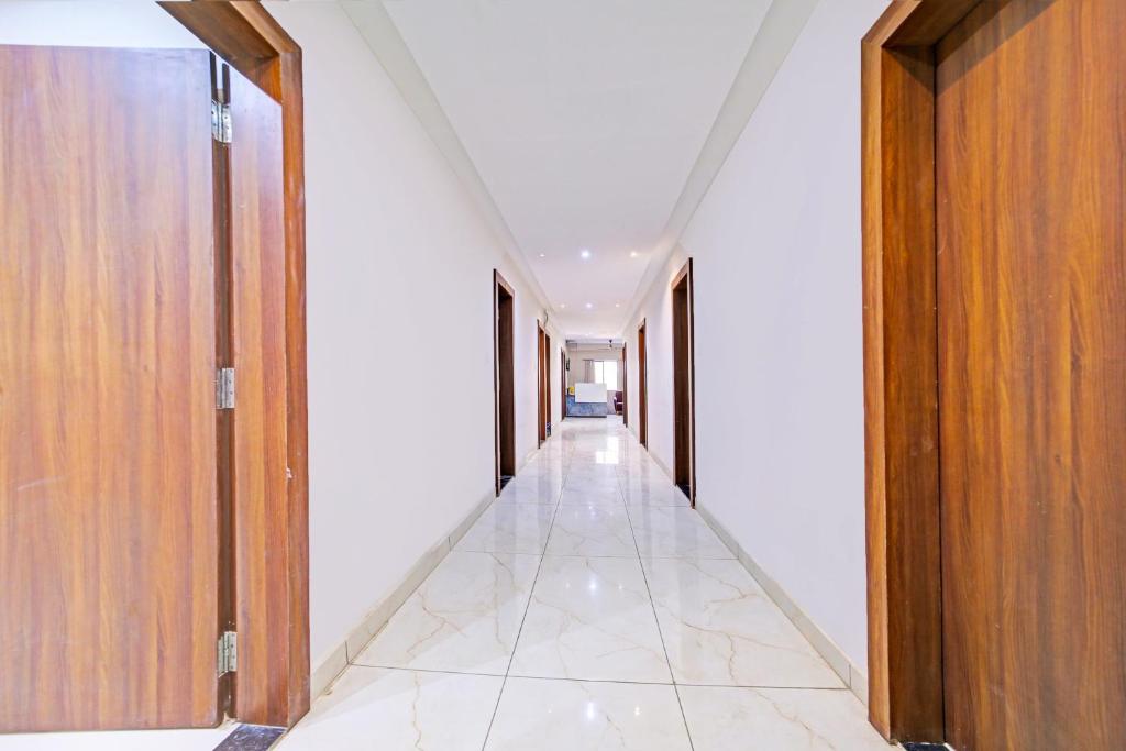 a corridor in a building with wooden doors and a tile floor at Super Townhouse LIG Main Road Indore in Indore