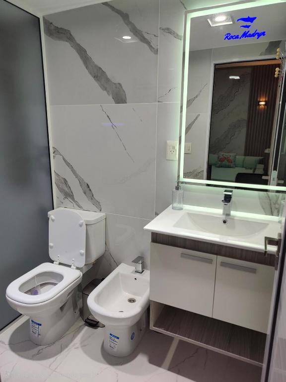 a bathroom with a toilet and a sink and a mirror at Roca Madryn in Puerto Madryn