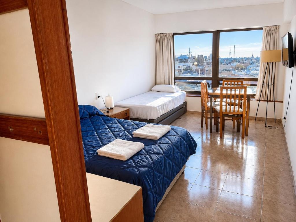 a bedroom with a bed and a dining room with a window at APART CyJ OBELISCO in Buenos Aires