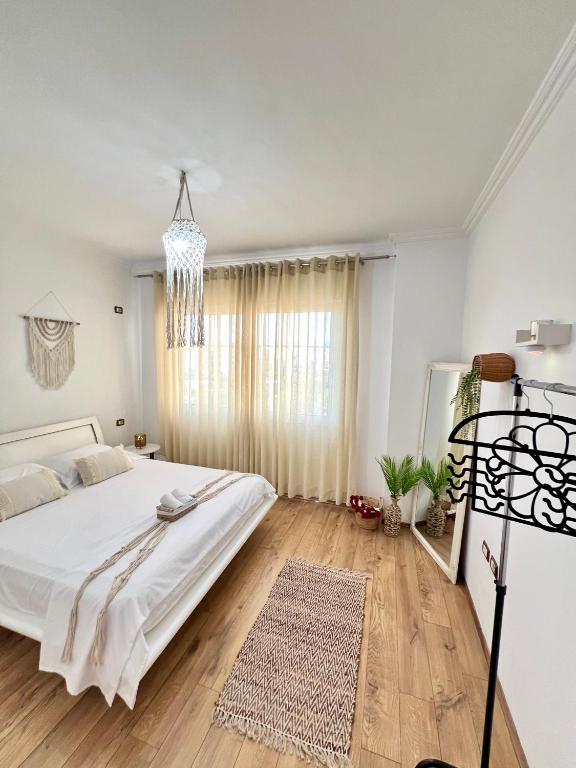 a white bedroom with a bed and a chandelier at Casa Trio in Tirana