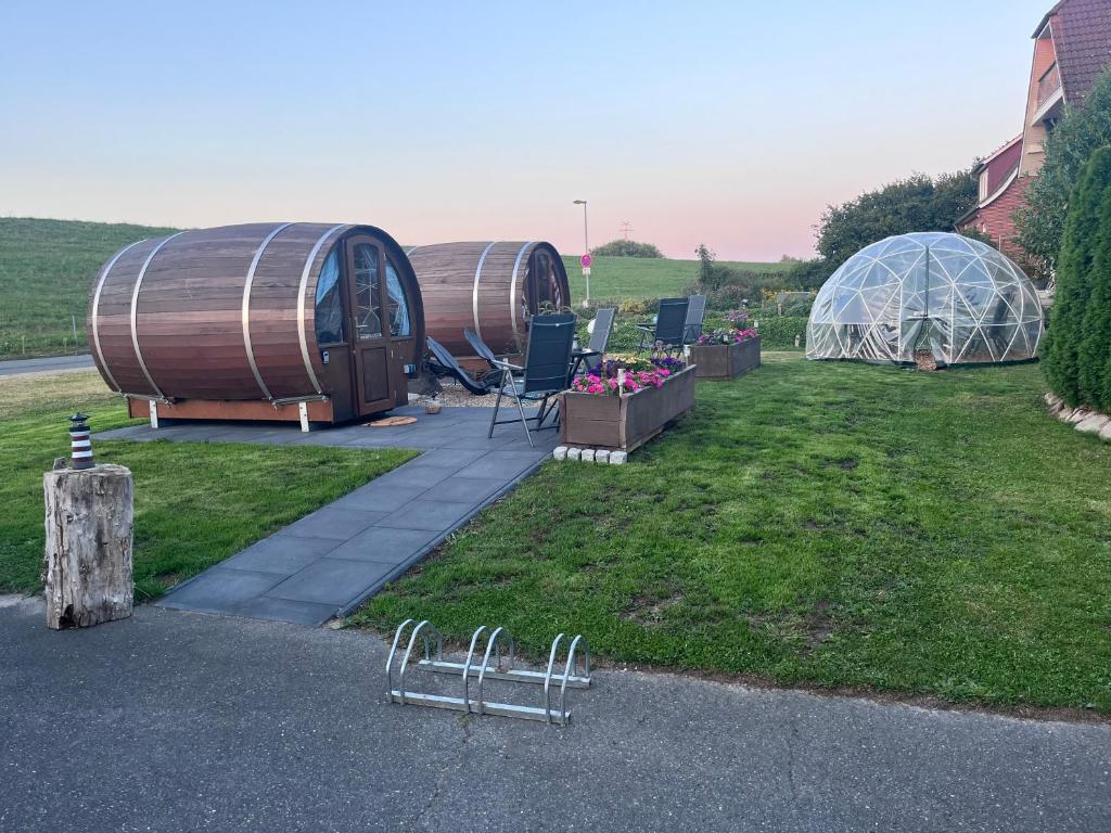 a couple of domes and a greenhouse in a yard at Claashoff Übernachtungsfass in Hollern-Twielenfleth