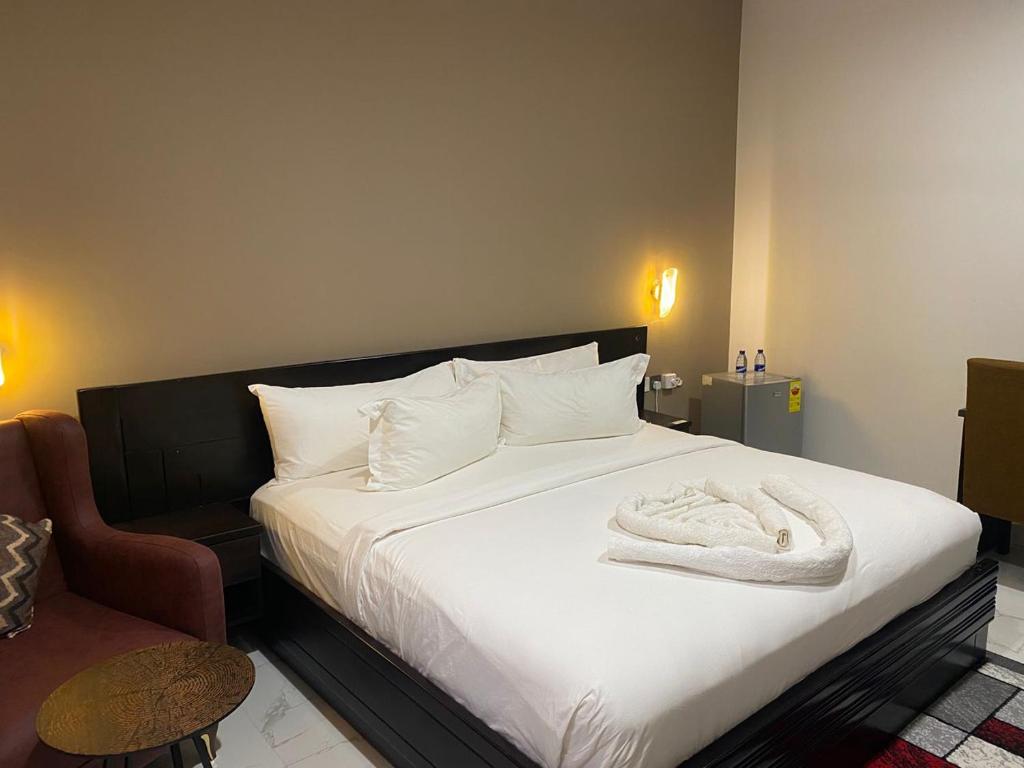 a bedroom with a white bed and a chair at Snl Mountain View Hotel in Oko Sombo