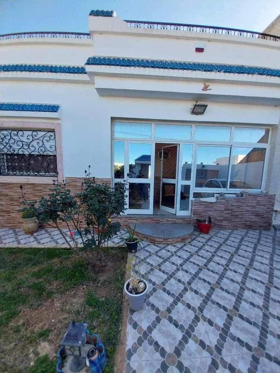 a white house with glass doors and a patio at Yamina's Holiday in Raoued