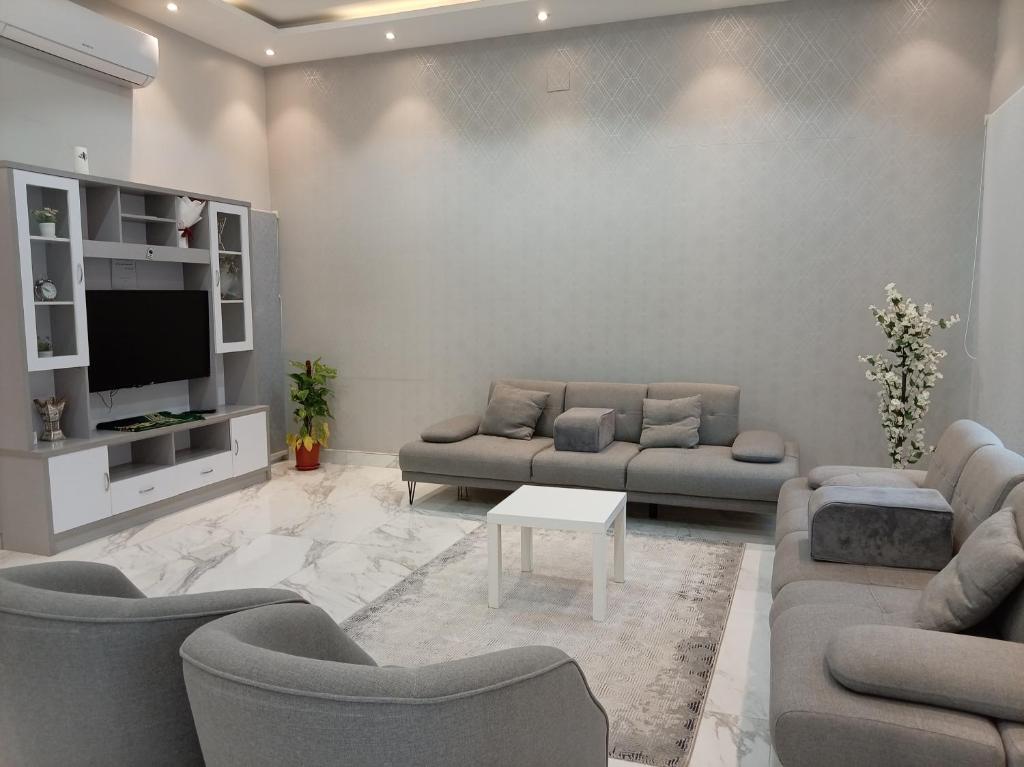 a living room with couches and a flat screen tv at شاليه ريف المملكة in Hail