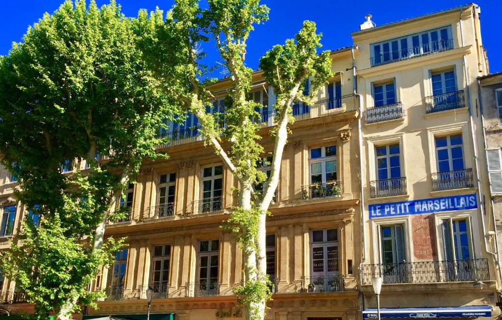 un grand bâtiment avec des arbres devant lui dans l'établissement Les Suites du Cours & Spa, à Aix-en-Provence