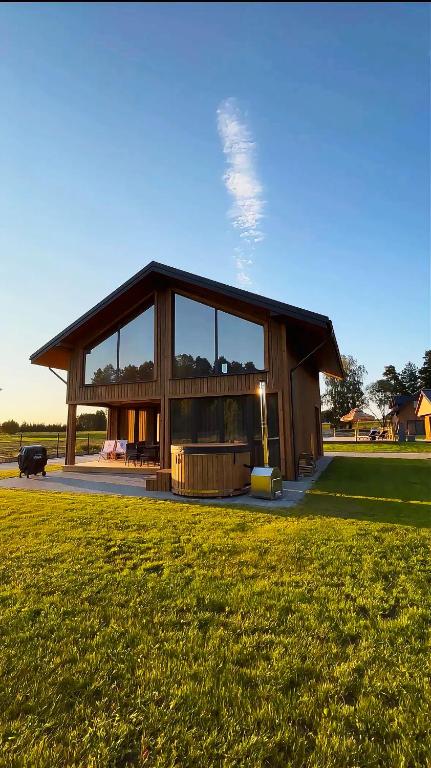 a large wooden house with a large window at Z Nurtem Rzeki Domy z basenem Podlasie in Korycin