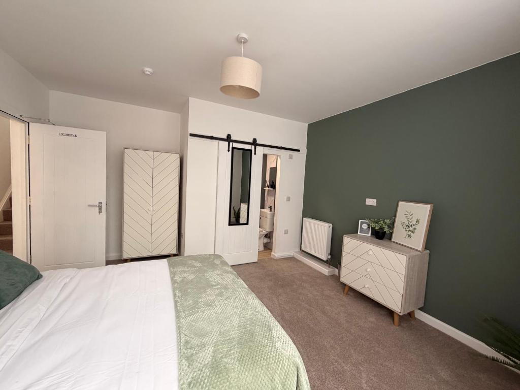 a bedroom with a white bed and a green wall at Brook Terrace in Darlington