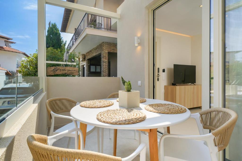 a white table and chairs on a balcony with a tv at Villa Yanna in Olympiada