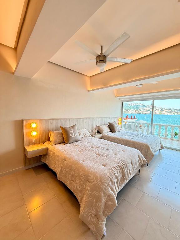 two beds in a bedroom with a large window at Suite Deluxe frente al Mar - Playa & GYM in Acapulco