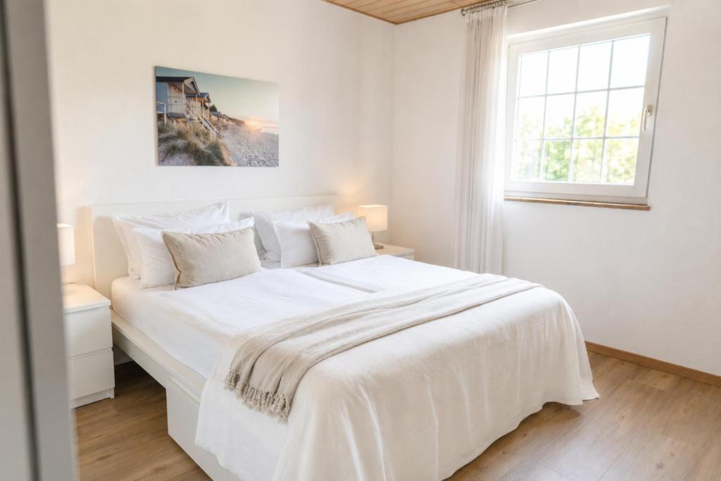 a white bedroom with a large white bed and a window at Idyllische Wohnung mit Weitblick in Neukirchen-Vluyn